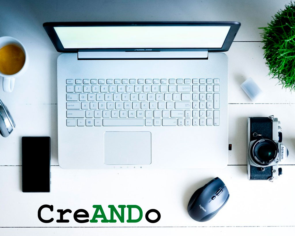 Mesa de escritorio con un portátil, un móvil y una cámara de fotos