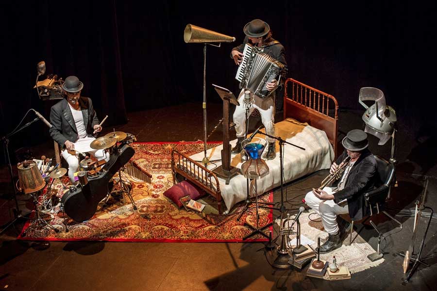 Tres intérpretes rodeados de instrumentos y objetos inusuales, creando un ambiente teatral de experimentación sonora